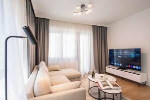 Ein modernes Wohnzimmer mit einem großen Flachbildfernseher, einer Couch, einem Couchtisch und einer Stehlampe.