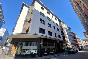 Ein mehrstöckiges Hotel mit einer gewölbten Fassade, einem Außenbereich zum Sitzen und einem gut sichtbaren Eingang.