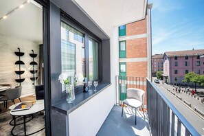 Un balcon moderne avec un coin repas, un vase rempli de fleurs et une vue sur la ville.