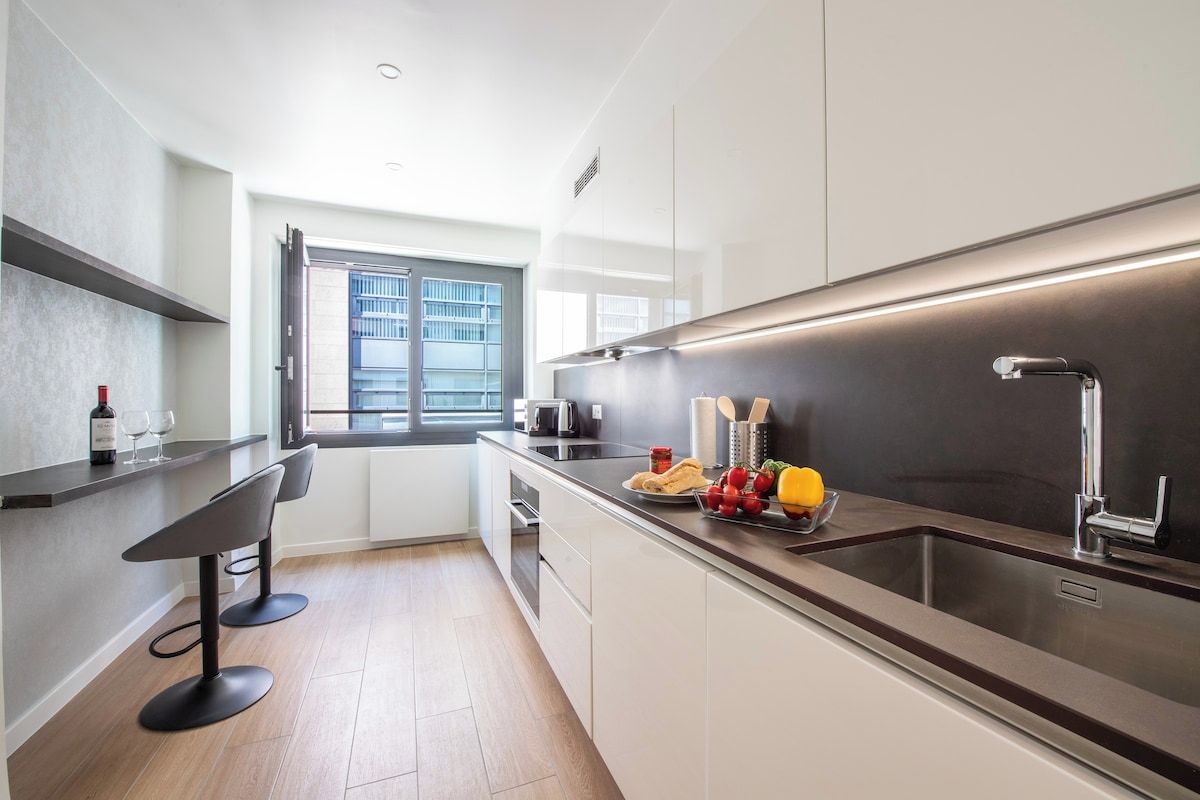Eine moderne Küche mit Backofen, Spüle aus Edelstahl und einem Fenster mit Blick ins Freie.