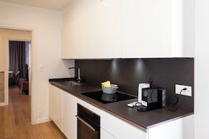 A modern kitchen with white cabinets, a black countertop, and a built-in stove. - Boutique Suites Two Bedroom Apartment with AC (Lugano)