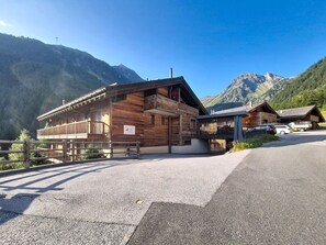 A wooden building with a balcony, a paved driveway, and mountains in the background. - Nice apartment for 7 people with WIFI, TV, balcony and panoramic view (Grimentz)