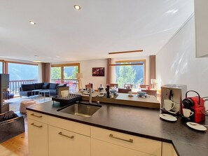 A modern kitchen with a central island, a dining area with a table and chairs, and a living area with a sofa and a TV. - Nice apartment for 7 people with WIFI, TV, balcony and panoramic view (Grimentz)