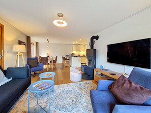 Ein modernes Wohnzimmer mit einer Couch, einem Couchtisch und einem Flachbildfernseher.