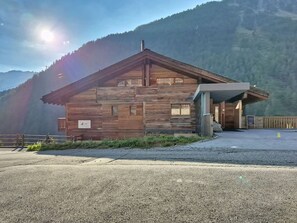 Une cabane en bois avec un toit en pente, une véranda et une allée gravillonnée.