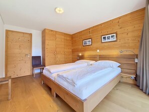 Une chambre à coucher avec un lit en bois, une chaise et une armoire.