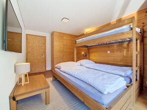 Ein Zimmer mit einem Etagenbett, einem Schreibtisch mit Lampe und einem Spiegel an der Wand.