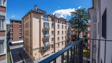 A multi-story residential building with balconies, a clear sky, and a tree in the background.