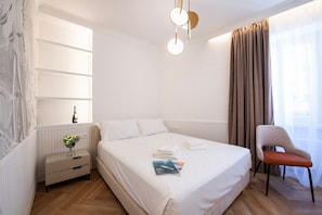 Una habitación de hotel con una cama grande, una mesita de noche, una silla y un estante en la pared.