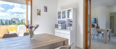 A modern kitchen with white cabinets and a dining area with a wooden table and chairs.