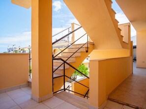 A spacious interior with a staircase leading to an upper level, featuring a tiled floor and a view of the sky. - Nice apartment for 6 people with WIFI, A/C, TV and patio (Alghero)