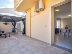 An outdoor patio area with a covered seating area, a water feature, and a view into a room with a dining table and chairs. - Nice apartment for 6 people with WIFI, A/C, TV and patio (Alghero)