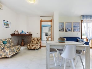 Ein Wohnzimmer mit einer Couch, einem Sessel und einem Esstisch mit Stühlen.