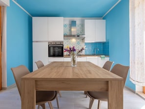 Eine moderne Küche mit weißen Schränken, einem schwarzen Backofen und einer blauen Spritzschutzwand.