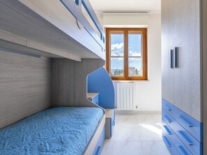 A bunk bed room with a window, a radiator, and a blue wall. - Nice apartment for 6 people with WIFI, A/C, TV and patio (Alghero)