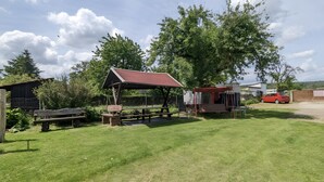 A picnic area with a covered bench, picnic table, and a small shelter. - Small, Cozy Apartment with Country Charm, Shared Garden & Wi-Fi (FeWo 4) (Hörselberg-Hainich)