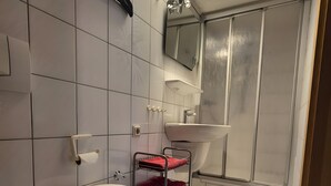 A bathroom with a toilet, sink, and shower area. - Small, Cozy Apartment with Country Charm, Shared Garden & Wi-Fi (FeWo 4) (Hörselberg-Hainich)