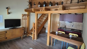 A wooden interior with a TV, wooden staircase, a dining area, and a kitchen. - Small, Cozy Apartment with Country Charm, Shared Garden & Wi-Fi (FeWo 4) (Hörselberg-Hainich)