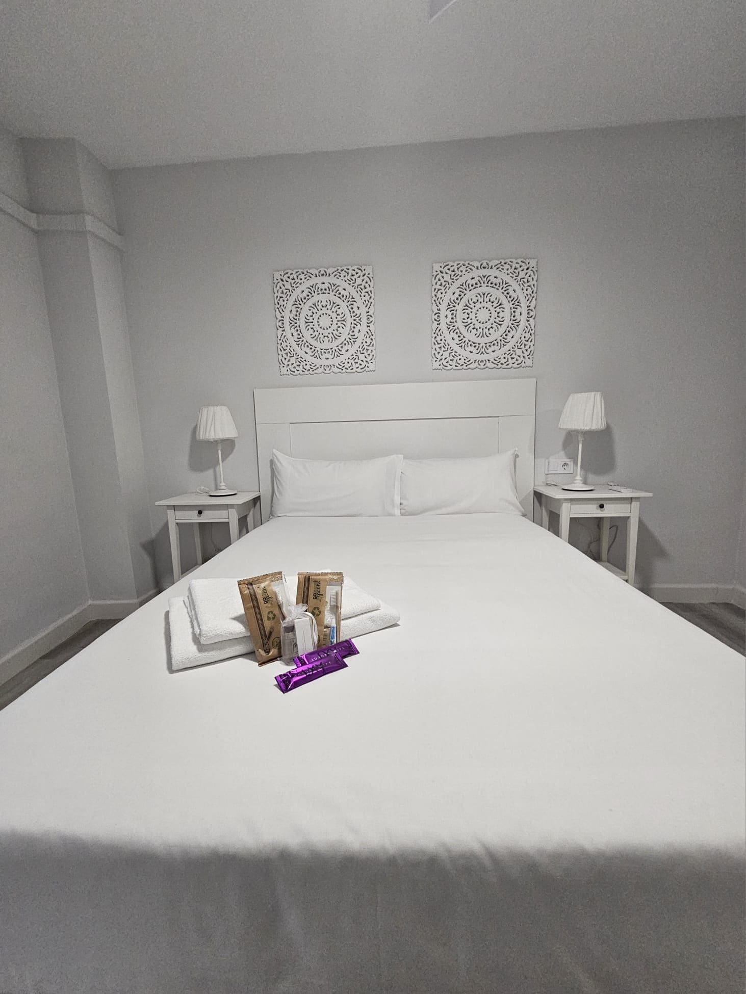Quarto de hotel com uma cama grande, duas mesas de cabeceira e arte decorativa na parede.