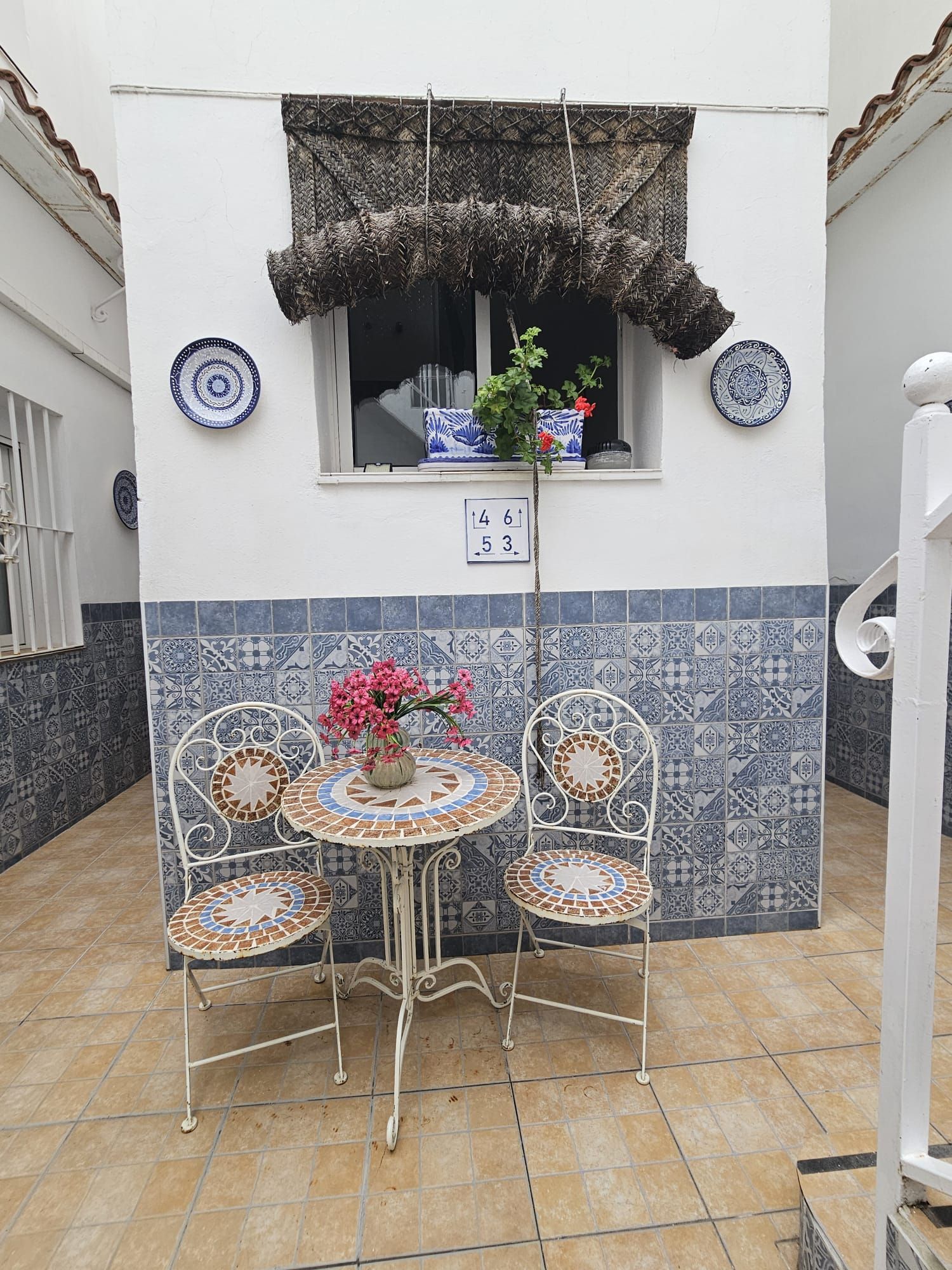 Un patio con dos sillas, una mesa y platos decorativos.