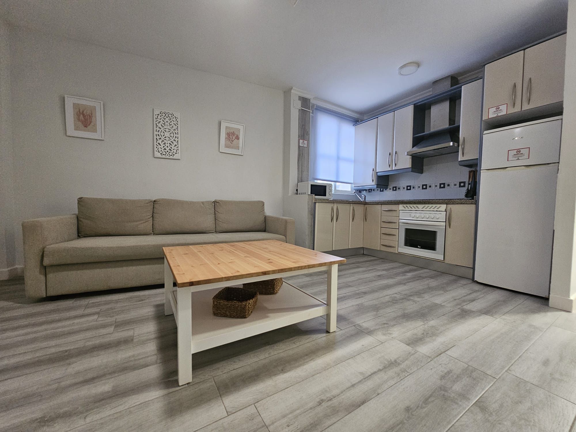 Una cocina funcional con sofá, mesa de madera y microondas.