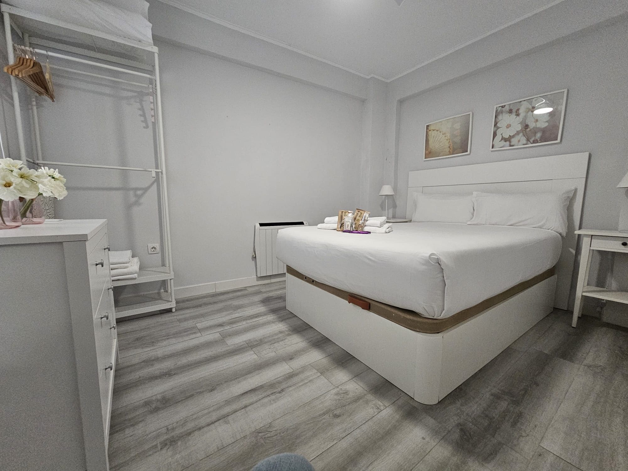 Un dormitorio con cama, mesita de noche, cómoda y vestidor.