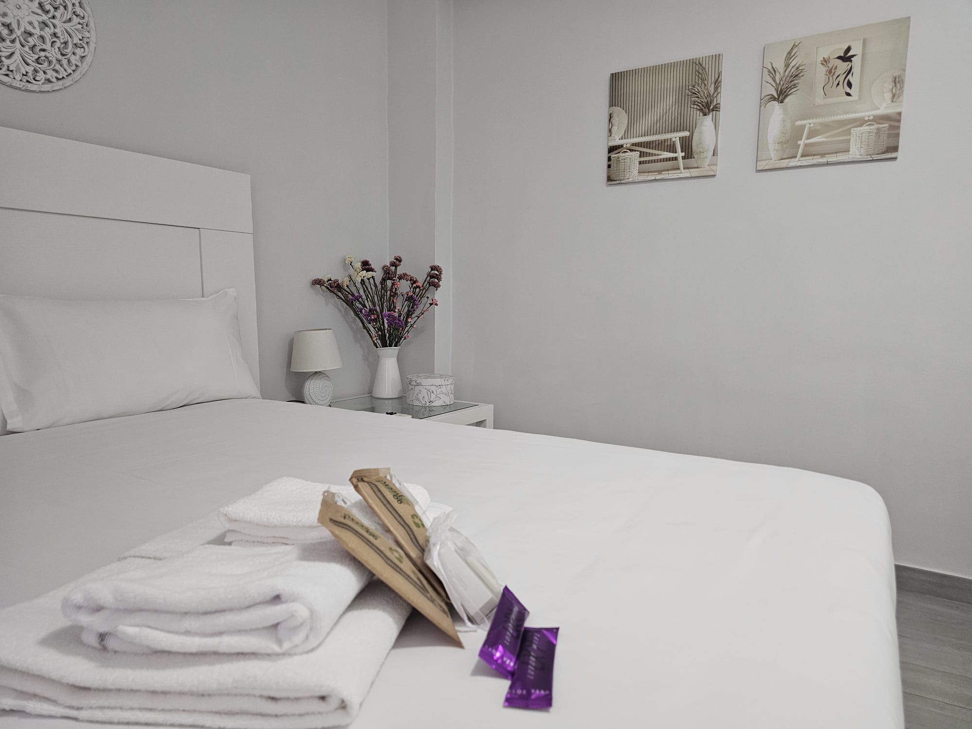 Un lit bien fait, avec des serviettes blanches pliées et un objet violet posé sur le côté.