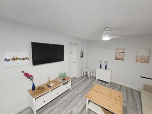 A modern living room with a flat-screen TV, a wooden coffee table, a white sofa, and a ceiling fan. - Puertas de la Catedral (Córdoba)