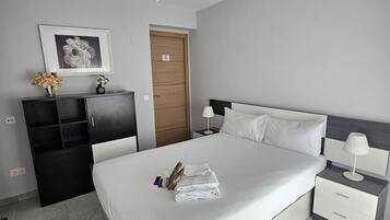 Una habitación de hotel moderna con una cama grande, una mesita de noche, un armario y un ventilador de techo, además de un cuadro en la pared.