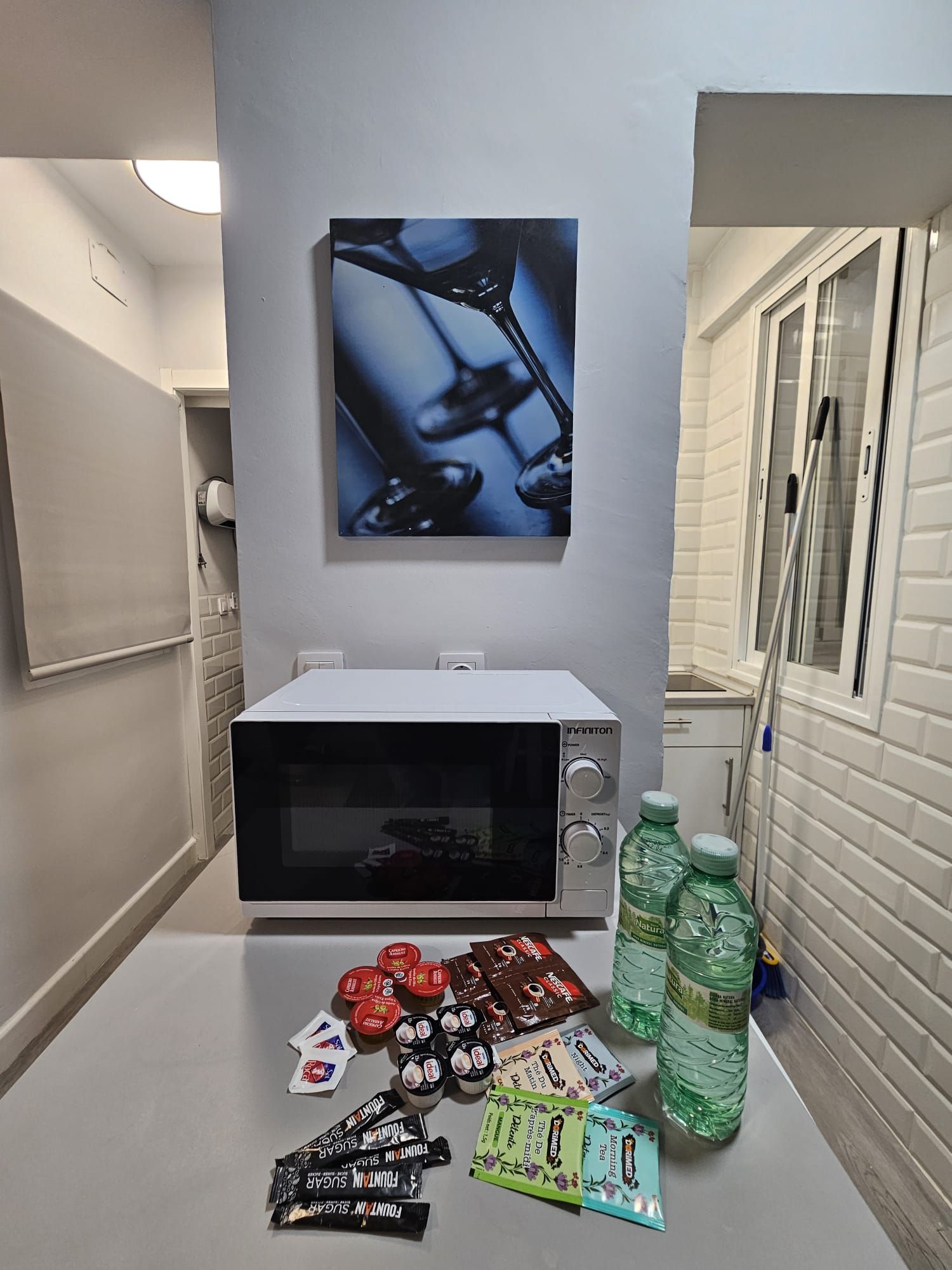 Een kitchenette met een magnetron, een koelkast en een raam.