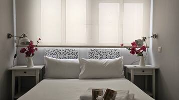 Une chambre d’hôtel avec un grand lit, deux tables de chevet, une tête de lit décorative et une fenêtre avec des rideaux.