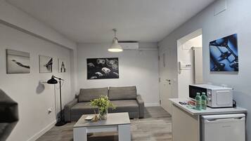 A modern living room with a grey sofa, a coffee table with a vase, and artwork on the walls.
