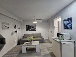Una sala moderna con un sofá gris, una mesa de centro con un florero y obras de arte en las paredes.