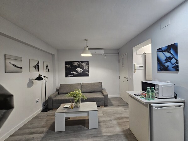 Una sala moderna con un sofá gris, una mesa de centro con un florero y obras de arte en las paredes.