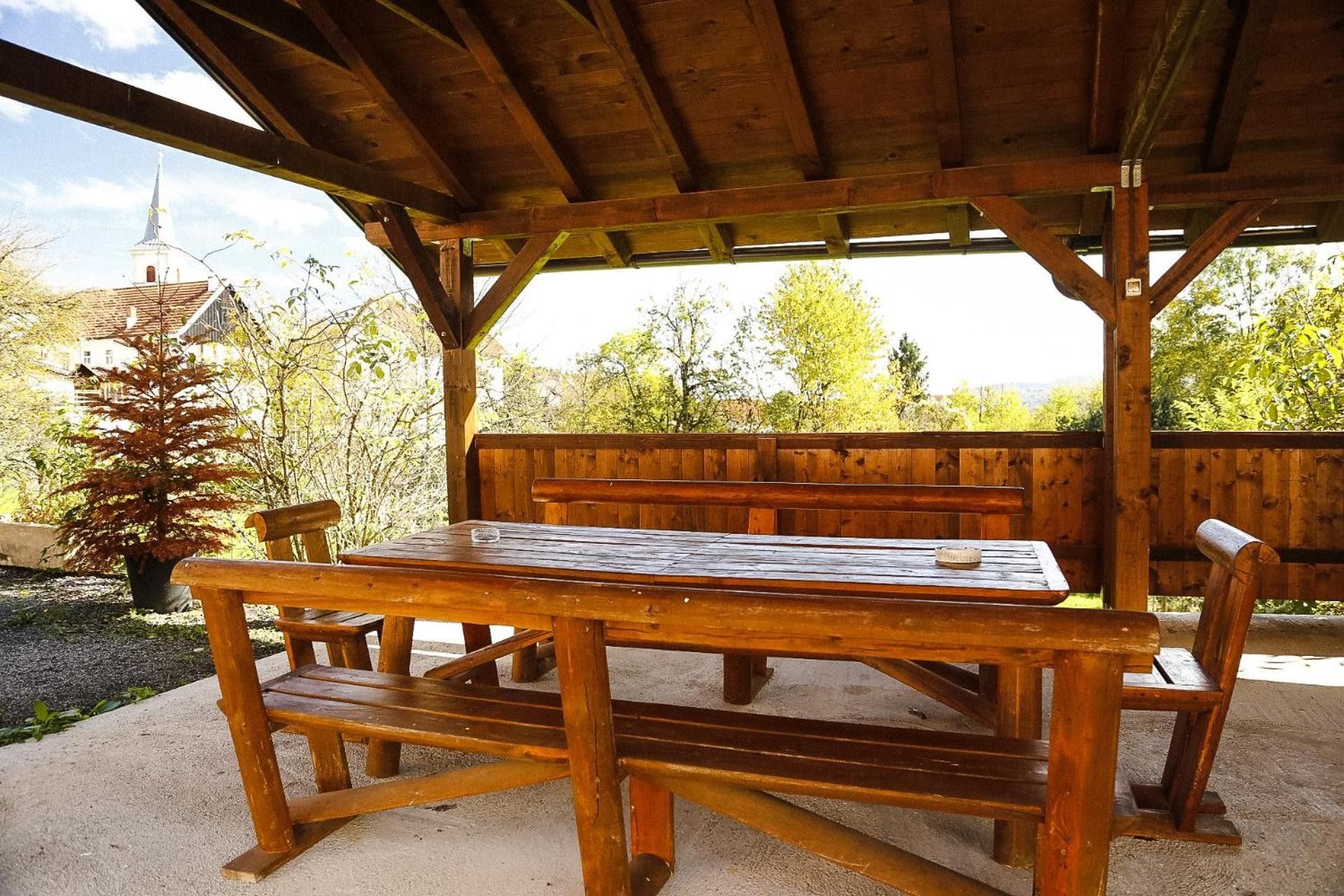 A wooden outdoor seating area with benches and a picnic table.