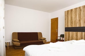 Ett hotellrum med en säng, en soffa, en trädörr och ett litet bord.