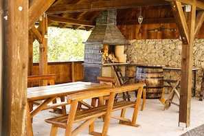 A rustic wooden outdoor dining area with a stone fireplace and a wooden bench. - Holiday Home 'Lukovdol' with Hot Tub and Sauna (Lukovdol)