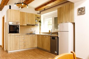 Eine Küche mit Holzausstattung, einem Einbauofen, einem Geschirrspüler und einem Kühlschrank.