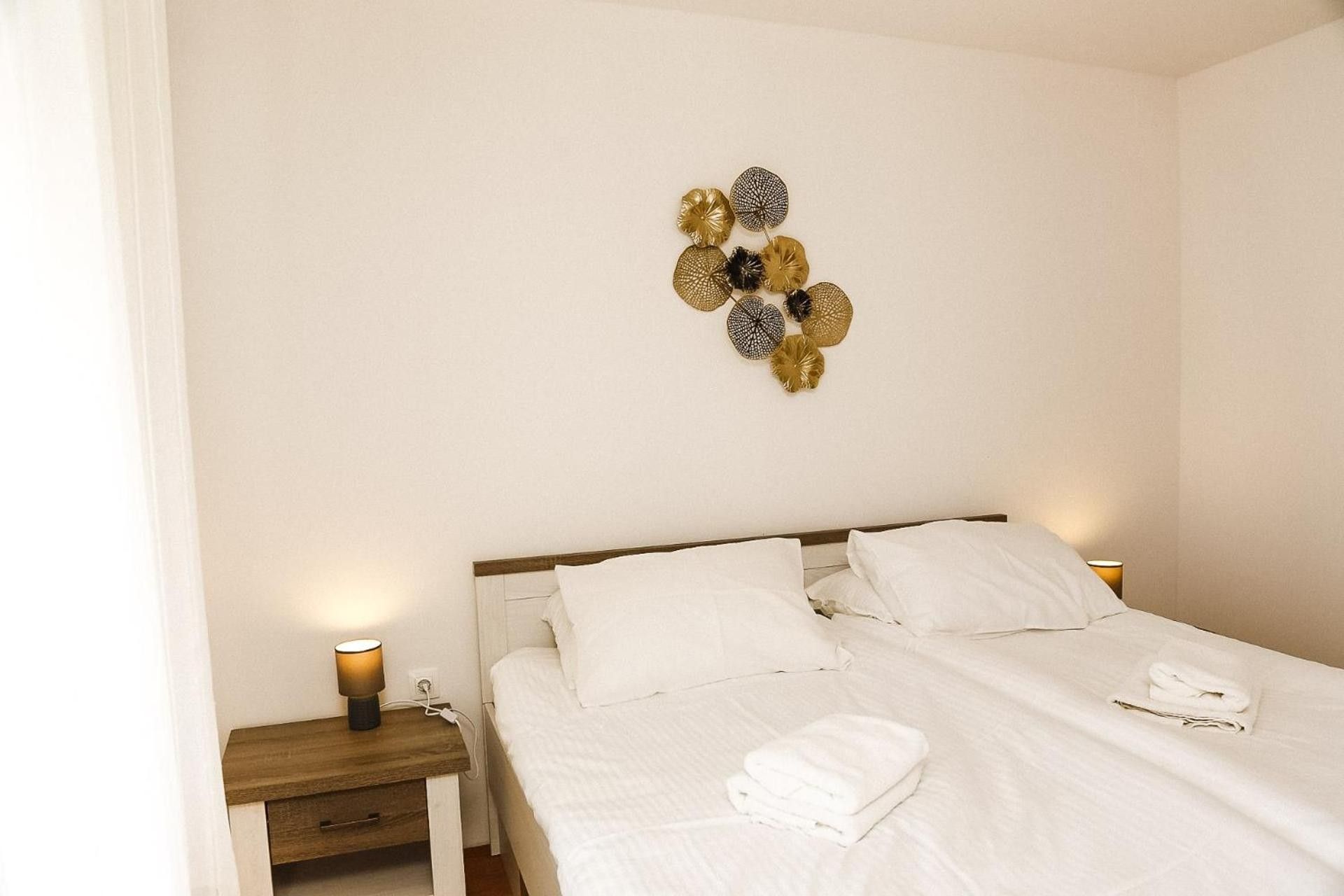 Ett hotellrum med en säng, ett sängbord med en lampa och en väggdekoration.