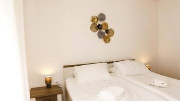 Ett hotellrum med en säng, ett sängbord med en lampa och en väggdekoration.