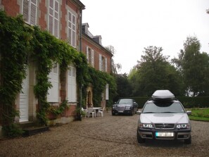 A gravel driveway leading to a building with a car parked in front.