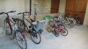Bicycles parked indoors with a concrete floor and stone walls.