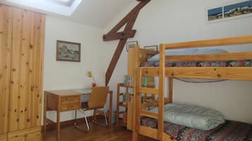 Ein Zimmer mit einem Etagenbett, einem Schreibtisch, einem Stuhl und einem Bücherregal.