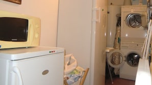 A compact kitchen with a refrigerator, microwave, and washing machine.