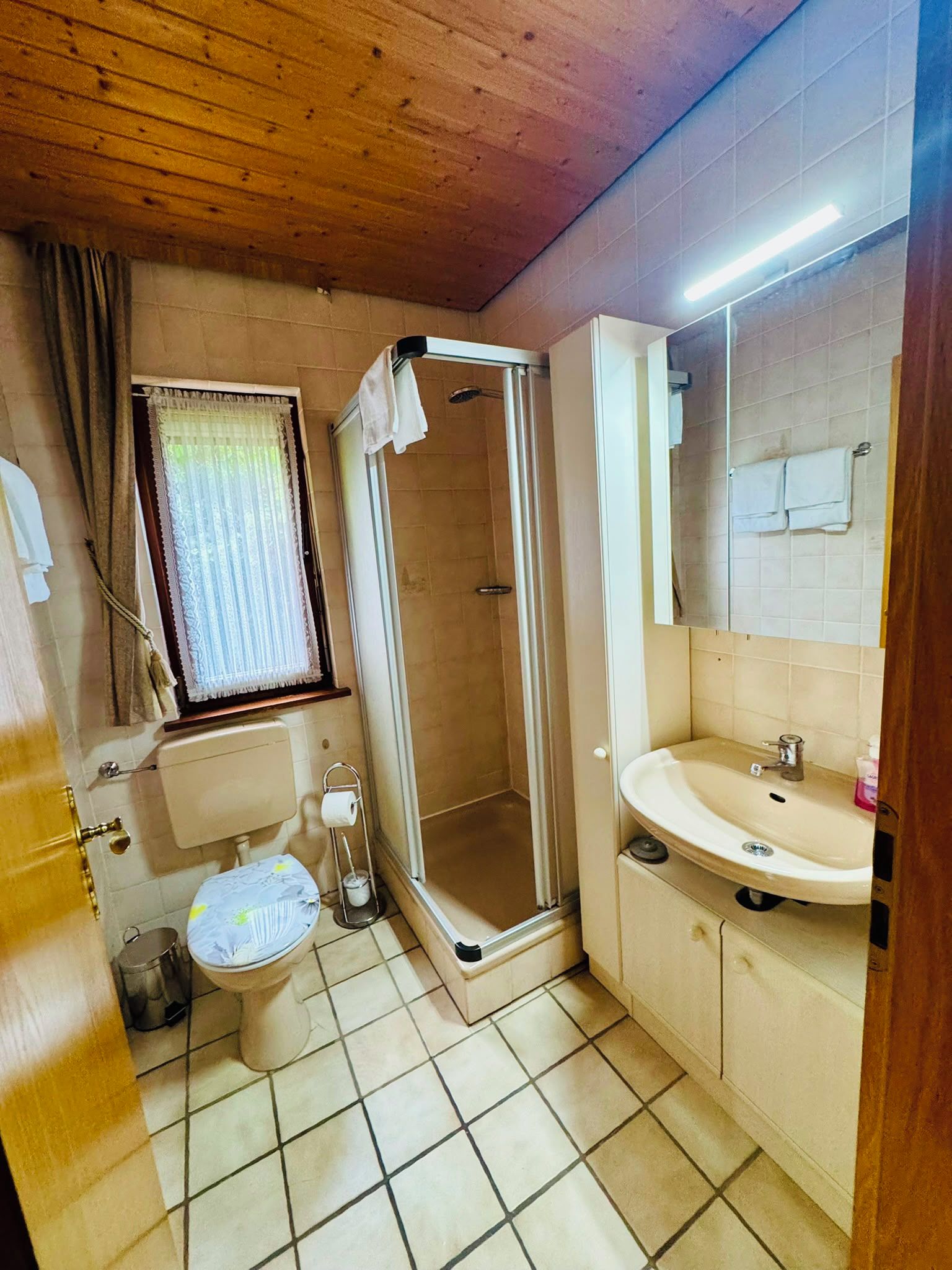 Une salle de bain équipée d’une douche, de toilettes, d’un lavabo et d’une fenêtre.