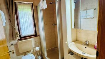Une salle de bain équipée d’une douche, de toilettes, d’un lavabo et d’une fenêtre.