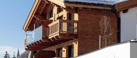 Un immeuble à plusieurs étages, doté de balcons en bois et d’une base en pierre, appelé « Tauron Lodge ».