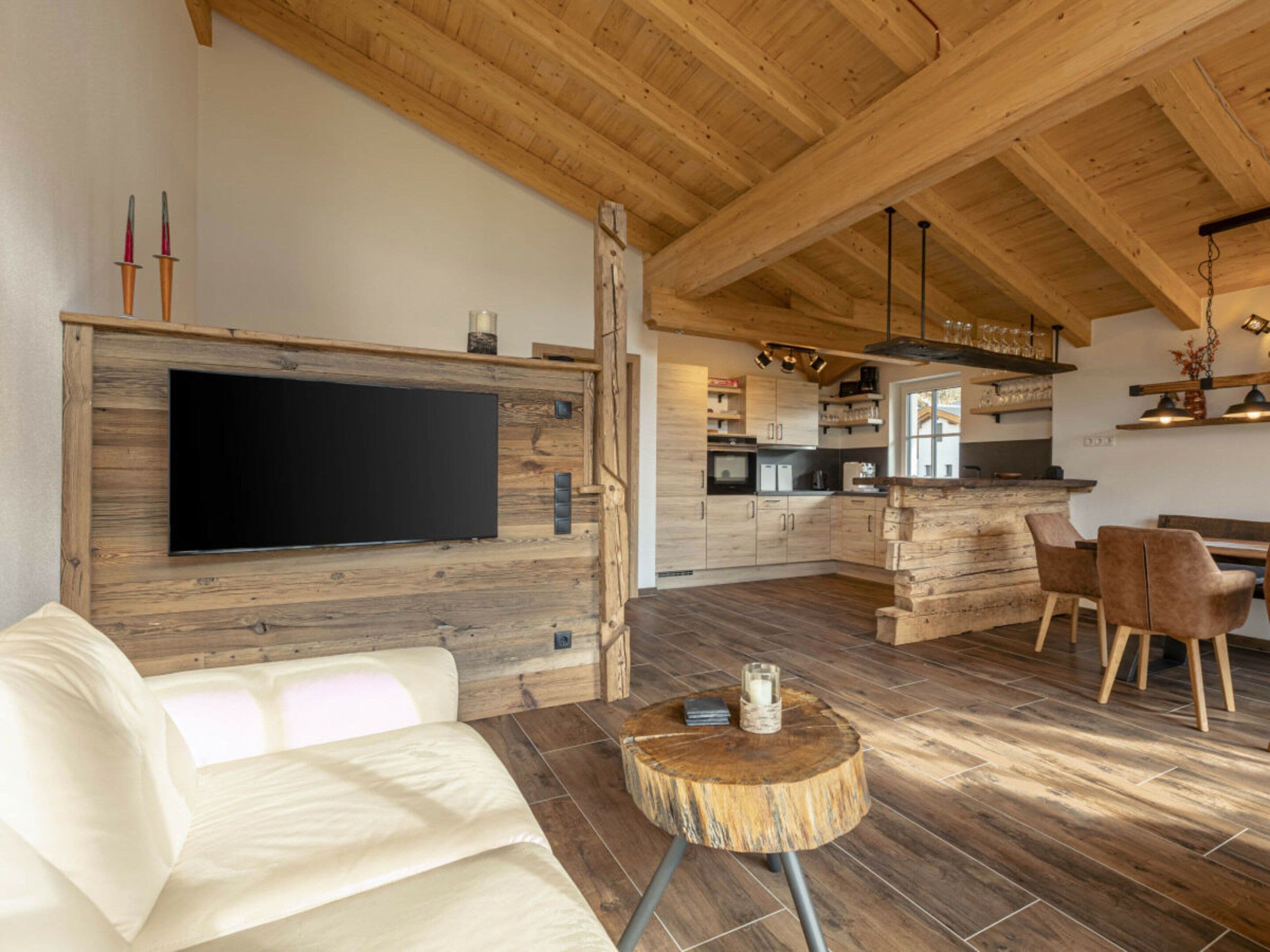A modern kitchen with wooden cabinets, a central island, and a dining area with chairs.