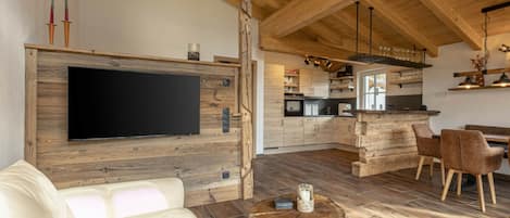 A modern kitchen with wooden cabinets, a central island, and a dining area with chairs.