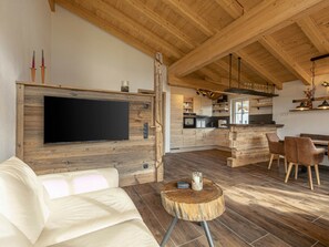 A modern kitchen with wooden cabinets, a central island, and a dining area with chairs. - Premium Holiday Home #1B With Sauna (Uttendorf)